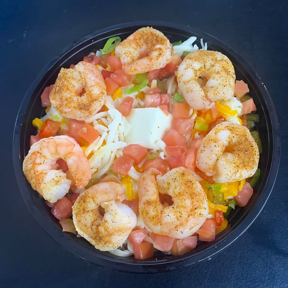Shrimp bowl with seasoned shrimp, diced tomatoes, bell peppers, shredded cheese, and a dollop of sour cream.