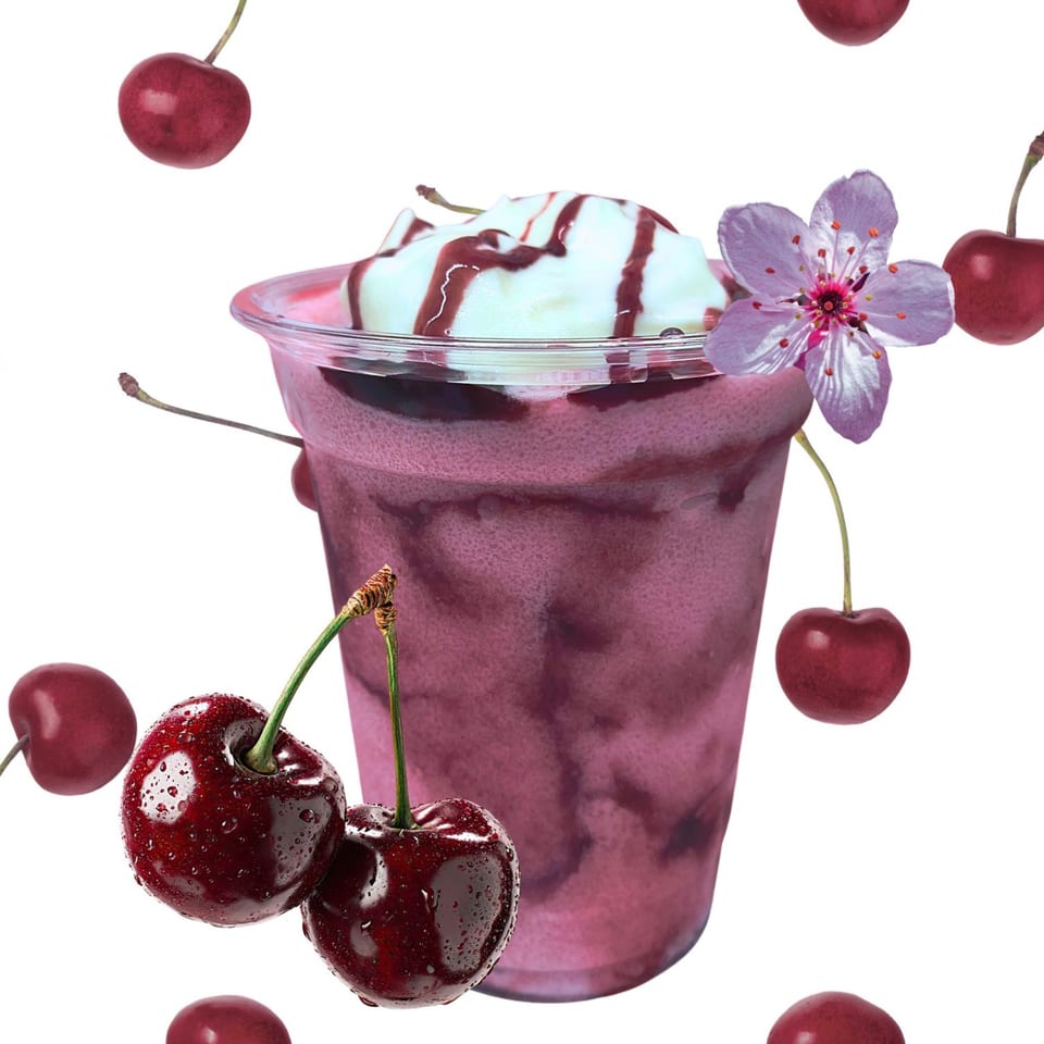 Cherry smoothie with whipped cream, chocolate drizzle, a pink flower, and fresh cherries.