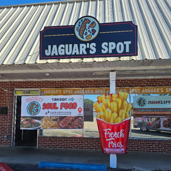 Jaguar's Spot restaurant exterior with a large sign, promotional banners, and a giant french fries inflatable.