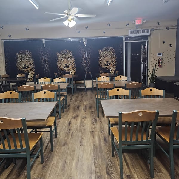 Jaguar's Spot dining room with wooden tables, green chairs, and jaguar-themed wall decor.