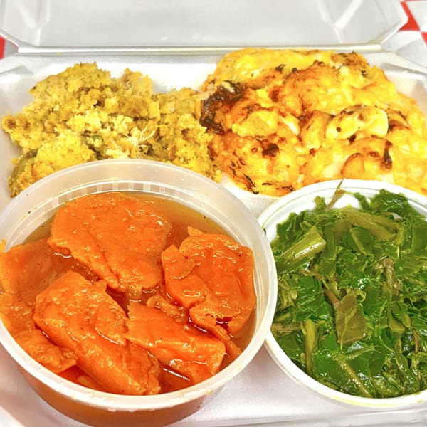 A takeout container with cornbread dressing, mac and cheese, candied yams, and collard greens.