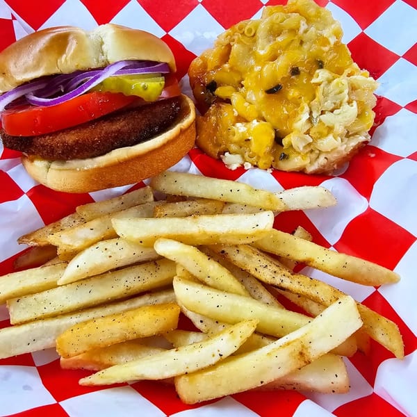 Jaguar's Spot burger with fries and mac and cheese on red and white checkered paper.