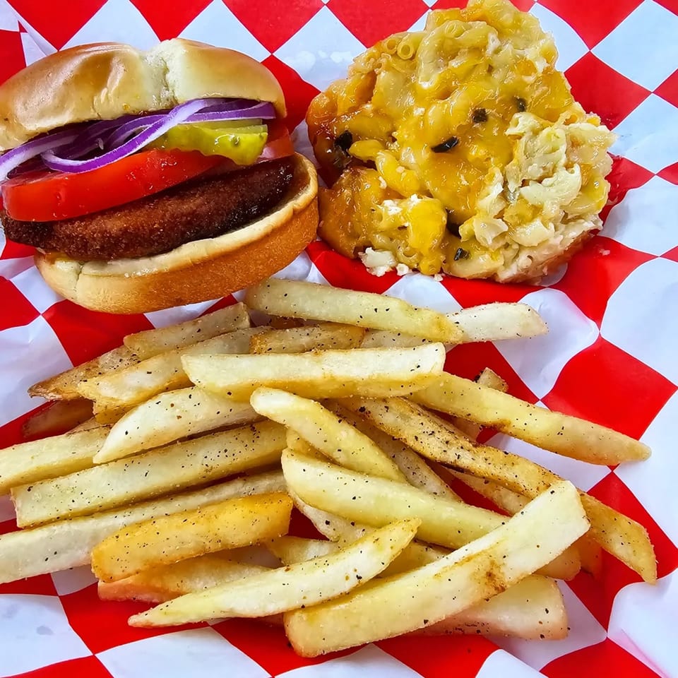 Jaguar's Spot burger with fries and mac and cheese on red and white checkered paper.