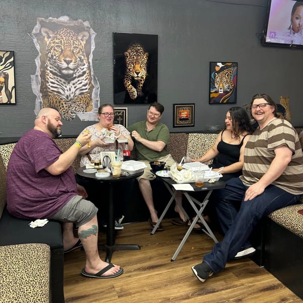 Five people eating and laughing at Jaguar's Spot, surrounded by jaguar-themed decor.