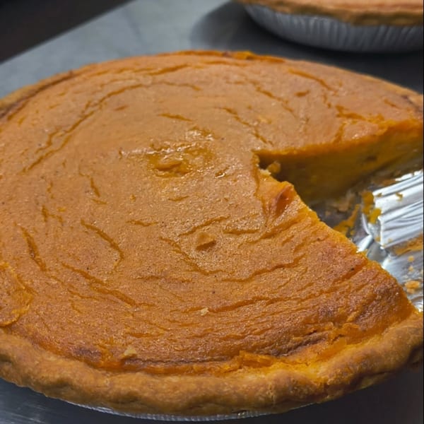 A golden-brown sweet potato pie with a slice removed, revealing the rich orange filling.