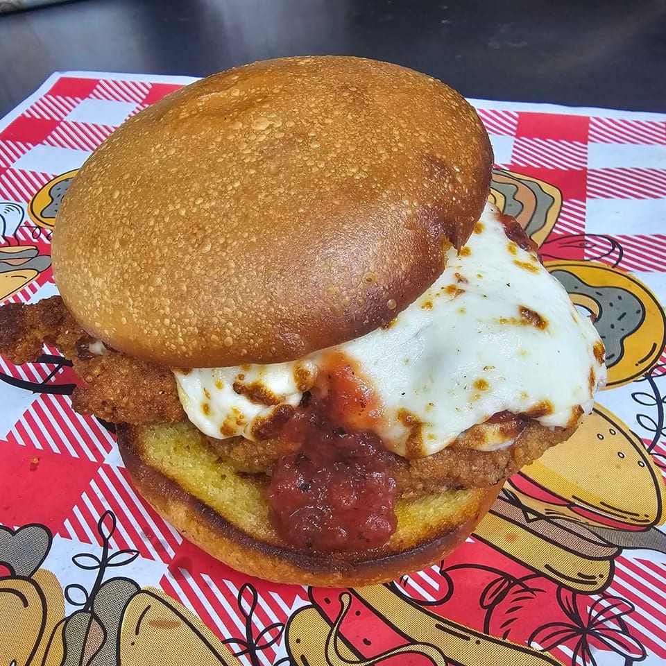 Chicken parmesan sandwich with melted mozzarella and marinara sauce on a toasted bun.